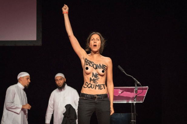 Two young women of Arab descent interrupting a debate on the various motives expressed in Sharia law justifying violence against women. “Nobody submits me,” wrote one of them defiantly on her chest. “I am my own prophet,” wrote the other. Women should not be coerced, forced, intimidated, beaten, they claimed … only to be kicked off the stage – literally and violently – confirming explicitly and unequivocally the very brutality imposed upon Muslim women that the conference was purportedly debating. (Screen capture via You Tube)